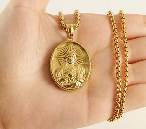 Close-up of 18K gold plated Sacred Heart of Jesus oval pendant necklace on a box chain