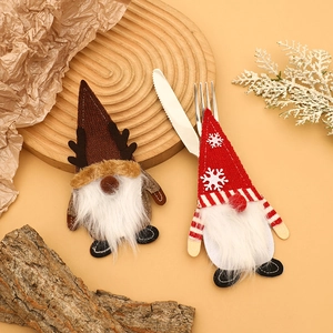 Porte-couverts de Noël gnome en tricot marron et rayé sur une table décorative de fête