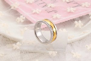 Detail of silver and gold wave-shaped stainless steel ring with micro-set diamonds
