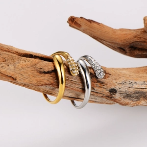 Gold and silver serpent rings with sparkling diamonds on a rustic textured branch