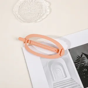 Close-up of matte peach-pink oval hair claw clip on minimalist lifestyle background