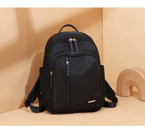 Detalle de mochila negra en tela Oxford con cremalleras doradas y bolsillos laterales