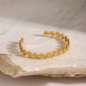 Macro shot of 18k gold stainless steel daisy bracelet with zircon on a stone