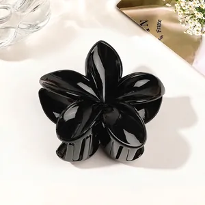 Close-up of a glossy black flower hair claw clip with a reflective mirror finish
