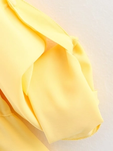 Detailed close-up of yellow fabric texture and high-quality stitching on a summer shirt