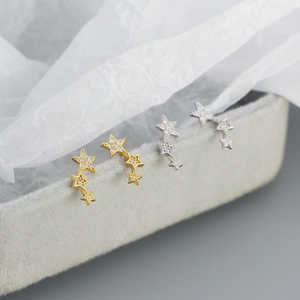 Detailed close-up of gold and silver S925 star stud earrings with sparkling cubic zirconia