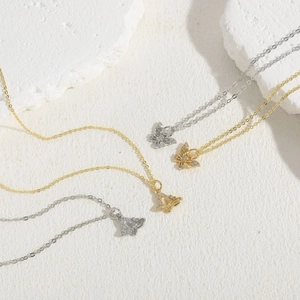 Detailed close-up of butterfly pendants in gold and silver with cubic zirconia inlays