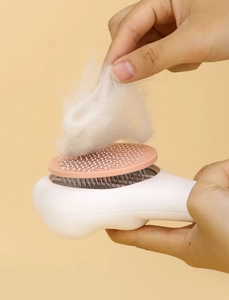 Détail de la brosse autonettoyante pour animaux avec manche patte de chat et tête rose