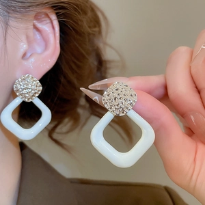 Detailaufnahme der geometrischen Ohrringe mit gehämmertem Silber und weißem Anhänger