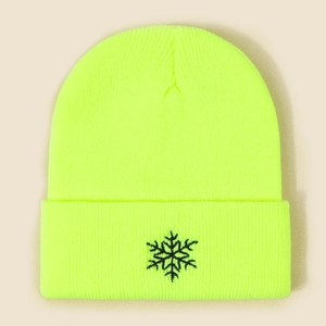Détail d'un bonnet en maille jaune fluo avec broderie de flocon de neige noire