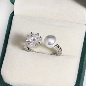 Detail of silver clover ring with zircon stones and a pearl on a twisted rope band