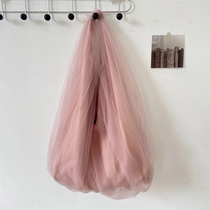 Detail of pink mesh tote bag showing layered fabric texture on a minimalist wall hook