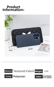 Detail view of black quilted wallet with metal cat ear decor next to a mobile phone