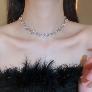 Close-up of a silver heart pearl necklace with rhinestones on a female neck