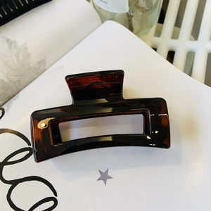 Detail of dark brown amber hair claw clip with geometric hollow rectangular design