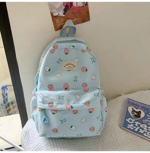 Close-up of cute strawberry and heart print patterns on a light blue nylon school backpack