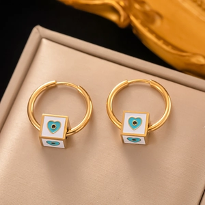 Goldene Creolen mit blauem Herz und Auge des Bösen Anhängern auf Schmucktablett