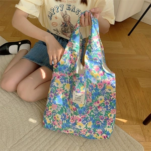 Dettaglio della borsa shopping in tela a fiori con motivi vintage e toppa logo centrale