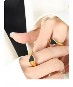 Close-up of two adjustable 18k gold plated titanium rings with black heart enamel