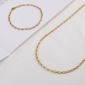 Gold minimalist oval link chain necklace and bracelet jewelry set on white background