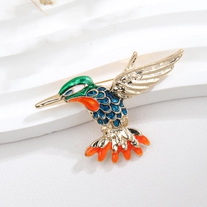 Close-up of hummingbird brooch featuring vibrant green and blue enamel with gold plating