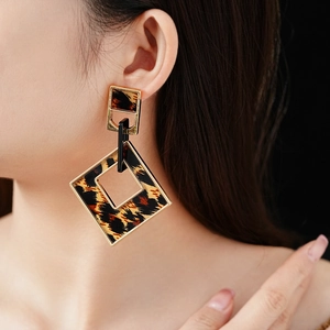 Close-up of leopard print geometric earrings featuring gold frames on a model