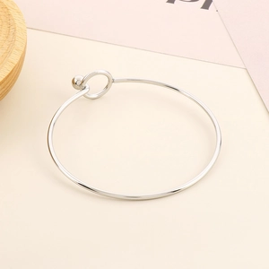Detailed close-up of a silver minimalist open bangle with a spherical clasp design