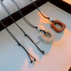 Detail of irregular hollow geometric pendants with amber and marble texture on cord chains