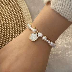 Elegant gold chain and pearl layered bracelet with a white floral shell pendant