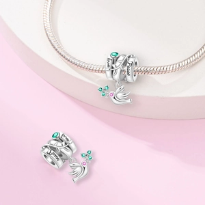 Macro detail of silver peace dove charm with green gems and Hope engraving on a bracelet