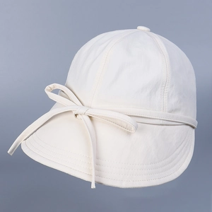 Detail of cream white sun hat featuring decorative fabric bow and reinforced stitching