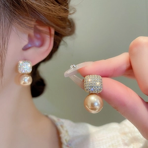 Gros plan de boucles d'oreilles papillon dorées avec zircon carré et perle d'imitation