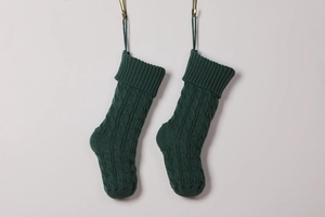 Close-up of two dark green knitted Christmas stockings with detailed cable knit texture