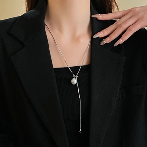 Close-up of a silver snake chain necklace with a white pearl on a model's neck
