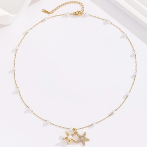 Detail of 18K gold-plated starfish pendant necklace with white pearls on a white background
