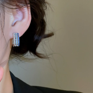 Detailed view of silver triple-row earring with white and blue cubic zirconia crystals