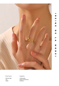Close-up of golden snake ring with scales worn on finger over white knitwear