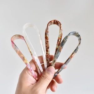Close-up of four U-shaped acetate hairpins with marble texture in various colors