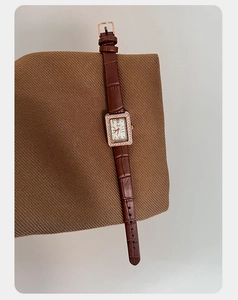 Dettaglio macro dell'orologio rettangolare in oro rosa con cristalli e cinturino marrone