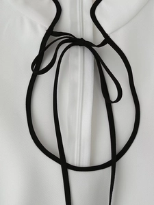 Detail of the stand collar with contrast black neckties and white resin zipper closure