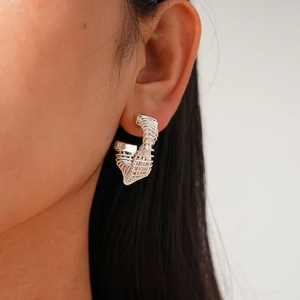 Detailed close-up of a silver twisted spiral hoop earring worn by a female model