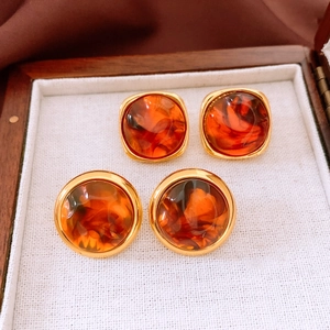 Macro view of vintage resin earrings with amber texture and gold plating in a luxury box