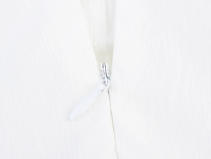 Detail view of a white invisible zipper with a teardrop puller on woven fabric
