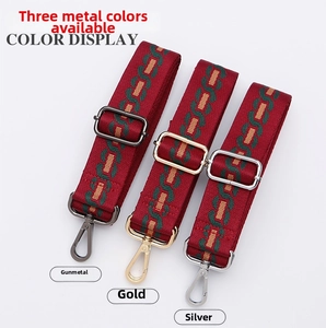 Macro detail of red and green striped bag strap with gunmetal, gold, and silver buckles