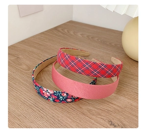 Three assorted floral and plaid fabric headbands displayed on a wooden surface