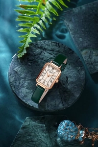 Close-up of elegant rose gold square watch with green leather strap and Roman numerals