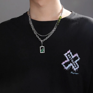 Detail of layered silver Cuban chain with pearls and green rectangular pendant necklace