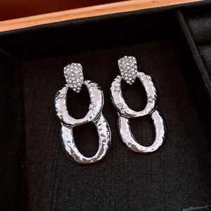 Close-up of silver interlocking oval drop earrings with cubic zirconia in a black box