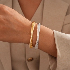 Detail of elegant gold and silver 18k plated crisscross bangles worn on a wrist