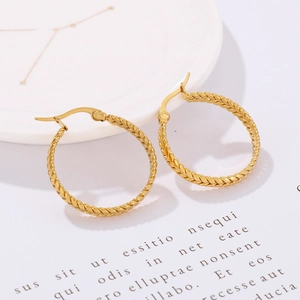 Detailed view of gold-plated geometric hoop earrings with braided wheat pattern texture